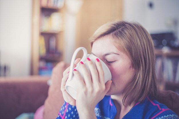 Zdjęcie ciesząc się filiżanką herbaty młoda kobieta pije filiżankę herbaty w domu zbliżenie