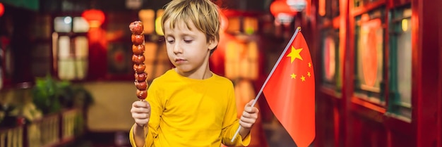 Cieszący się wakacjami w Chinach szczęśliwy turysta chłopiec z chińską flagą i tradycyjnym chińskim