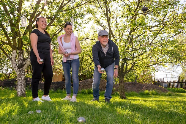 Cieszę się, że uśmiechnięta rodzina gra w francuską tradycyjną grę w petanque w ogrodzie na zewnątrz podczas pięknego letniego dnia, ciesząc się wolnym czasem