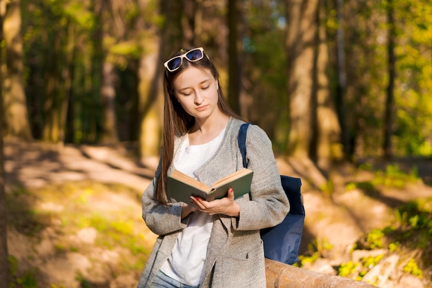 Cieszy się wolny czas Szczęśliwa dziewczyna czyta ciekawą książkę w parkowym lesie