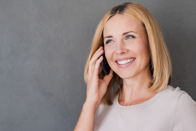Cieszyć Się Dobrą Rozmową. Radosna Dojrzała Kobieta Rozmawia Przez Telefon Komórkowy I Uśmiecha Się