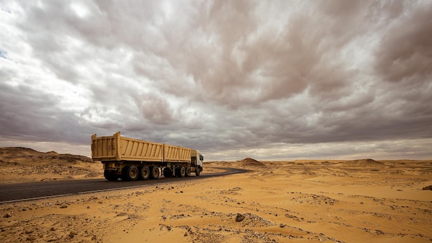 Ciężarówka jedzie drogą prowadzącą przez czarno-białą pustynię Egiptu