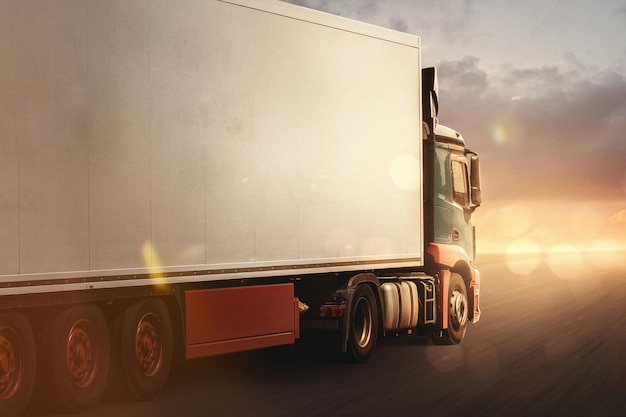 Zdjęcie ciężarówka jedzie szybko autostradą z promieniami słońca na horyzoncie w poświacie