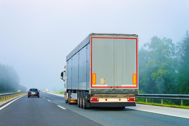 Ciężarówka po asfaltowej drodze Polski w mglistą pogodę. Transport ciężarowy dostarczający ładunek towarowy.