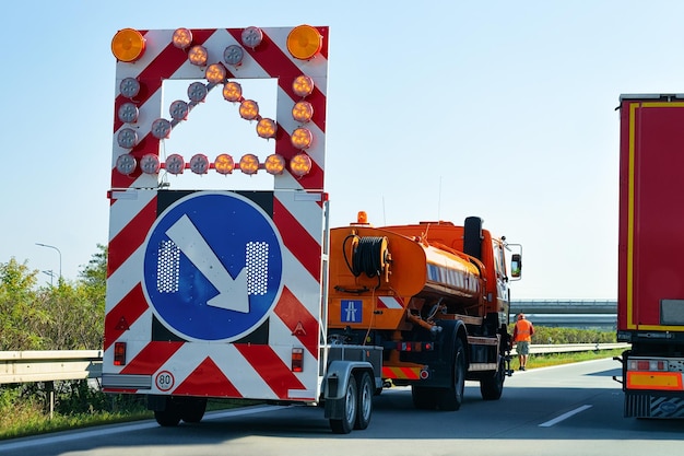 Ciężarówka przewożąca strzałkę w dół prawy kierunek odblaskowy znak drogowy w autostradzie w Polsce.