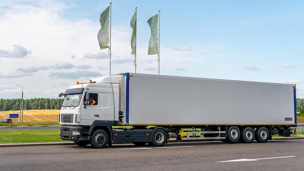 Ciężarówki z kontenerami na parkingu wzdłuż autostrady na tle chmur Koncepcja transportu logistycznego i transportu ładunków Miejsce spoczynku ciężarówek na parkingu