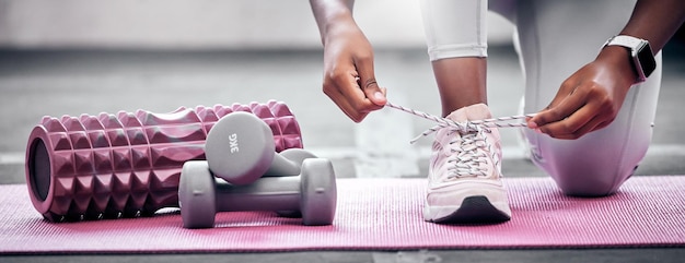 Ciężary fitness i kobieta wiążąca buty przed treningiem na siłowni dla zdrowia i siły Trening sportowy i zbliżenie sportowca ze sznurowadłami do zawiązania podczas przygotowań do ćwiczeń w centrum sportowym