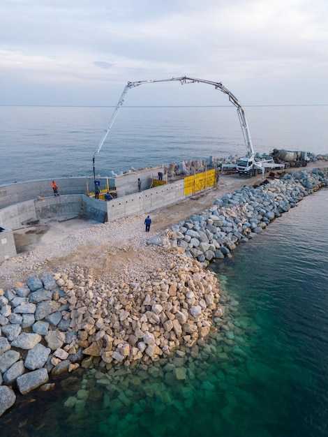 Ciężki sprzęt budowlany buduje falochron Wylewanie betonu na molo w budowie w morzu