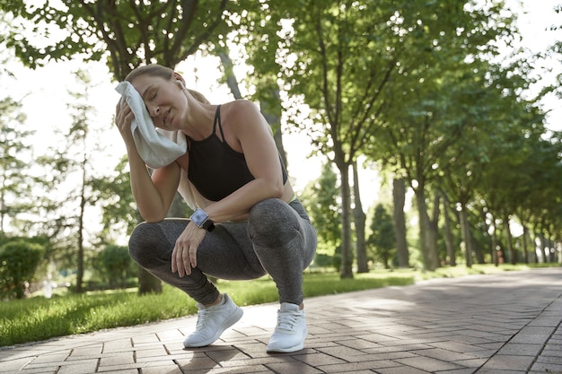 Ciężko pracująca zmęczona fitness kobieta w sportowej odzieży czuje się wyczerpana po aktywnym porannym treningu w