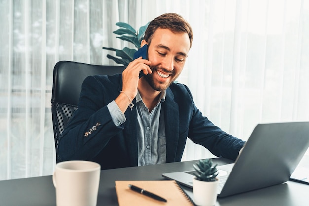 Ciężko pracujący i pilny biznesmen pracujący na swoim laptopie i telefonie.