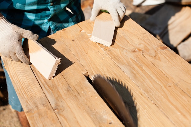 Ciężko pracujący stolarz tnący deski drewniane, skupiający się na piły