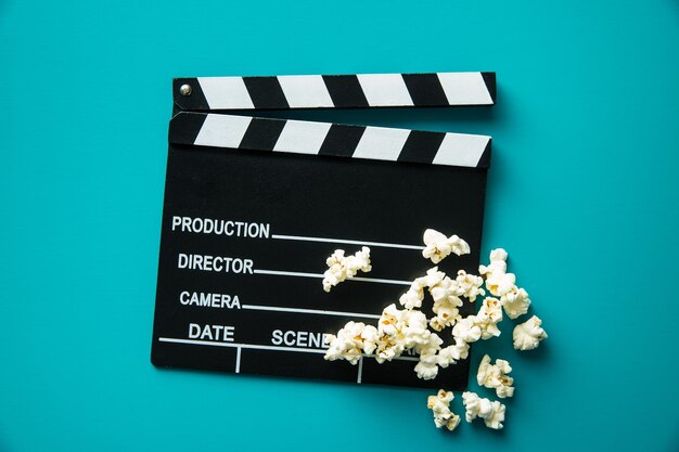 Clapperboard i popcorn na niebieskim tle Widok z góry