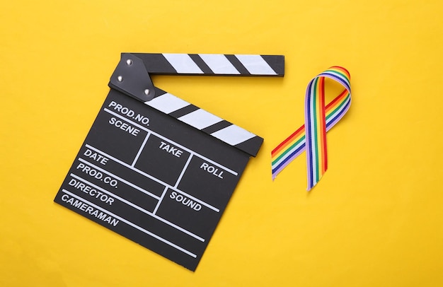 Clapperboard i tęczowa wstążka LGBT symbol taśmy dumy na żółtym tle