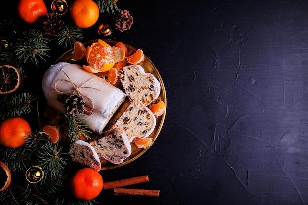 Zdjęcie classical stollen to tradycyjne niemieckie ciasto z rodzynkami i mandarynkami na ciemnym tle. ciasto owocowe na święta.