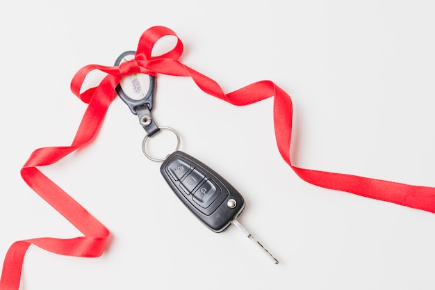 Zdjęcie close-up kluczyki do samochodu z czerwonym dziobem, jak obecny na białej tapecie