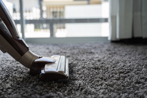 Close-up mężczyzna używa próżniowego cleaner podczas gdy czyścić w pokoju