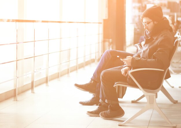 Close up.modern człowiek ze smartfonem siedzący w poczekalni na lotnisku