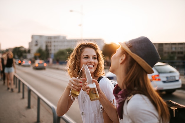 Close-up obraz dwie dziewczyny hipster co toast na zachodzie słońca.