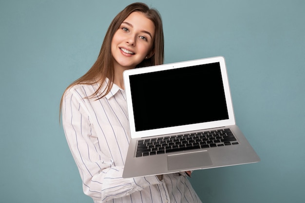 Close-up portret pięknej uśmiechniętej młodej kobiety trzymającej komputer netbook patrząc na kamerę