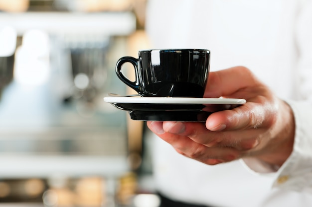 Coffeeshop - barista prezentuje kawę lub cappuccino