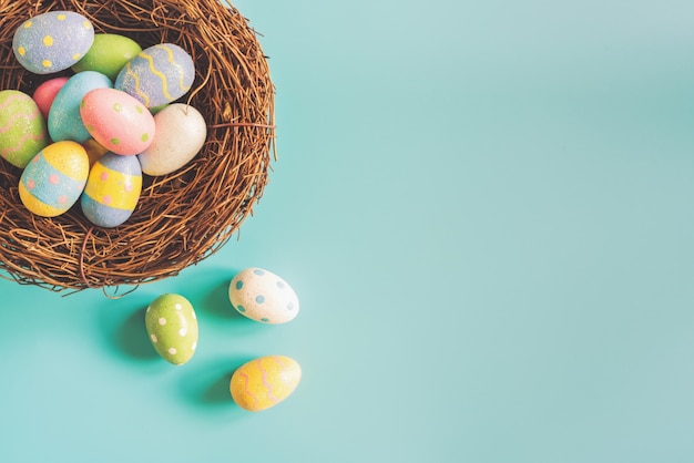 Coloeful Easter jajka w gniazdeczku na pastelowego koloru tle z przestrzenią.