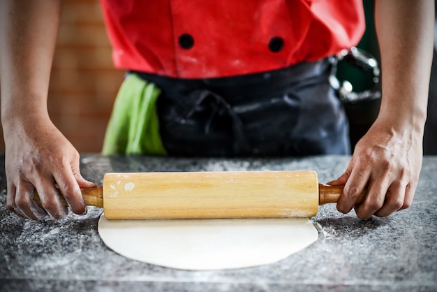 Cook rozwałkowuje ciasto na desce