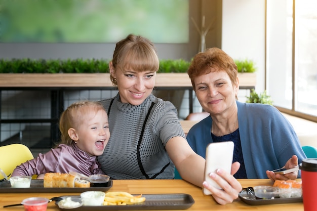 Córka babci i wnuczka są fotografowane przez telefon w kawiarni.