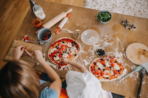 Zdjęcie córka i matka robią razem pizzę na kolację w kuchni