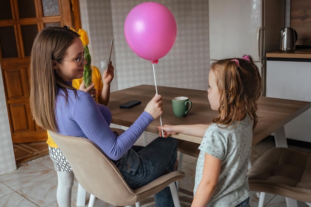 Córki gratulują mamie w Dniu Matki kartką z kwiatami i balonem