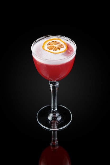 Zdjęcie cosmopolitan to kobiecy koktajl zamiast martini na bazie wódki triple sec likier cytryny i soku z żurawiny pij w szklance na ciemnym tle z odbiciem