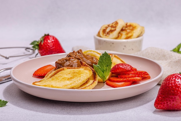 Cottage cheese pancakes syrniki curd fritters z miętą truskawkową i cukrem w proszku na różowym talerzu Selective focus delicious breakfast Trendy stone concrete background close up