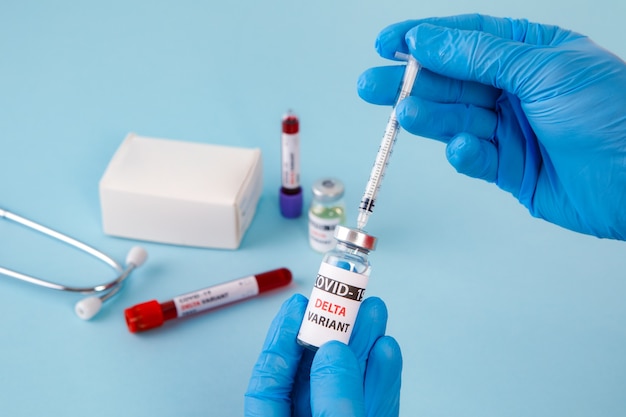 Covid 19 delta Wariant szczepionki i badania krwi w ręku na niebieskim tle. szczepienie przeciwko koronawirusowi