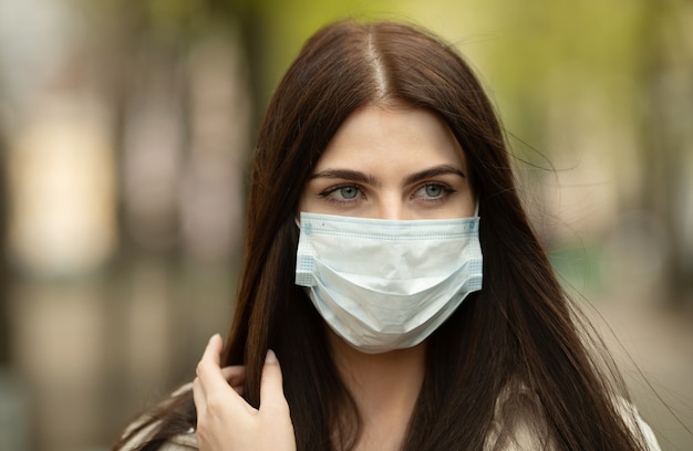 COVID-19 Koronawirus pandemiczny Kobieta na ulicy miasta ubrana w maskę ochronną przed rozprzestrzenianiem się wirusa choroby. Dziewczyna z maską ochronną na twarz przed chorobą Coronavirus 2019.