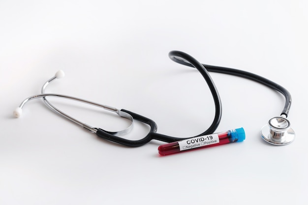 COVID-19 - Próbki krwi i stetoskop na białej powierzchni