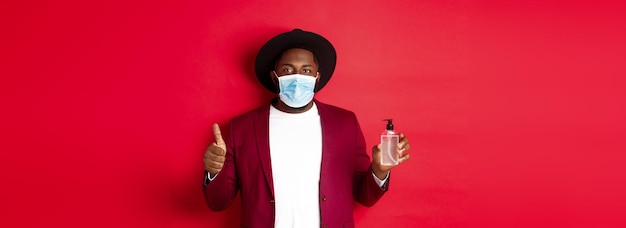 Covid koncepcja kwarantanny i wakacji młody afroamerykanin w masce medycznej pokazujący saniti dłoni