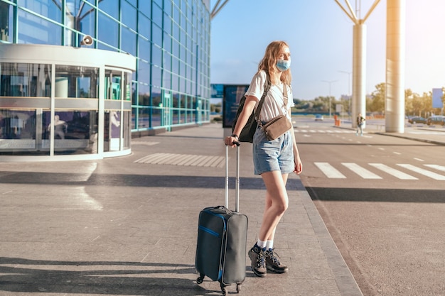 Covid travel lotnisko kobieta turysta z plecakiem i walizką stojącą w pobliżu międzynarodowego lotniska te...