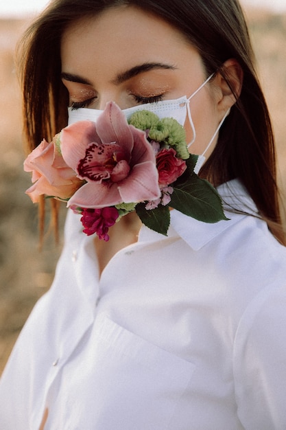 Zdjęcie covid19 piękna dziewczyna w sesji zdjęciowej maski kwiatowej