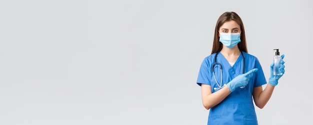 Covid19 zapobieganie wirusom zdrowie pracownicy służby zdrowia i koncepcja kwarantanny Młoda profesjonalna pielęgniarka lub lekarz w niebieskich zaroślach maseczka medyczna wskazujący palec na środek dezynfekujący do rąk