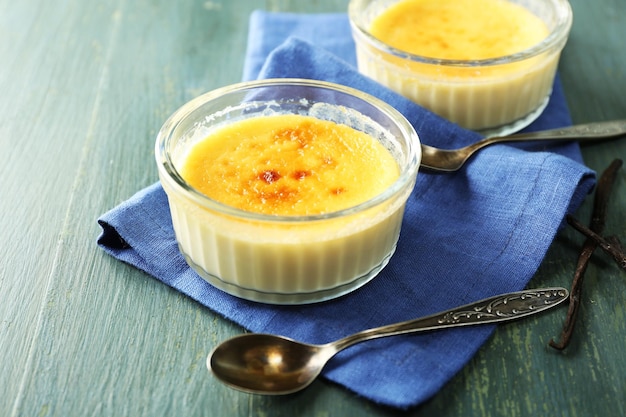 Creme brulee deser na serwetce na kolorowym drewnianym tle