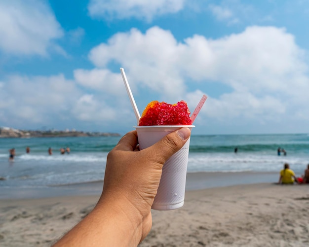 cremolada o smaku truskawkowym w białym szkle na plaży.