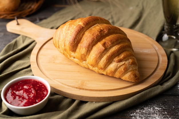 Zdjęcie croissant na drewnianym talerzu na wiejskim tle pyszne śniadanie z croissantem i dżemem