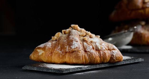 Croissant pieczony na desce i posypany cukrem pudrem czarny stół Apetyczne wypieki na śniadanie