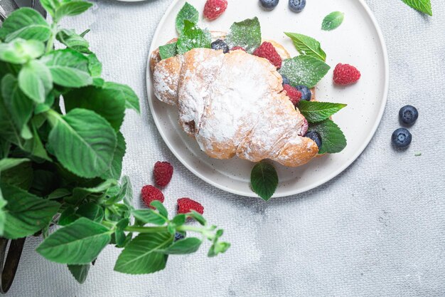 Croissant z malinami, jagodami i serem na białym talerzu