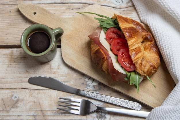 Croissant z szynką, serem, sałatką i pomidorami na śniadanie