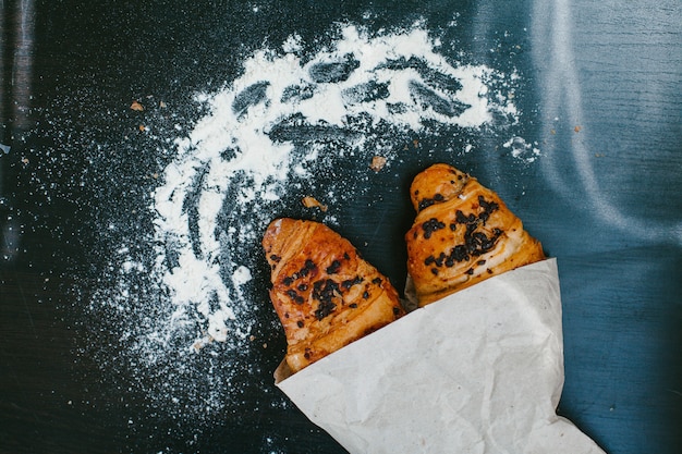 Croissants z czekoladą w papierze na ciemnym tle