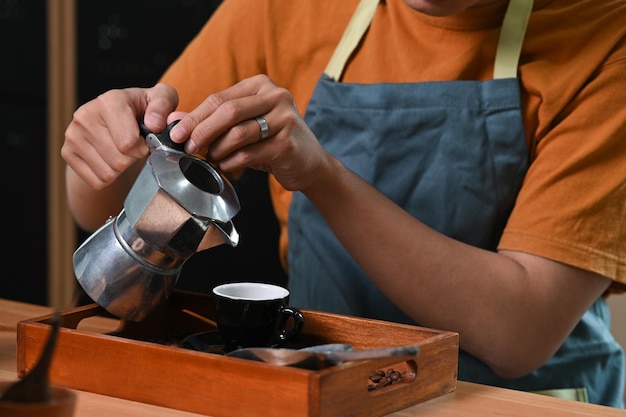 Cropped shot barista nalewający świeżą kawę z moka pot