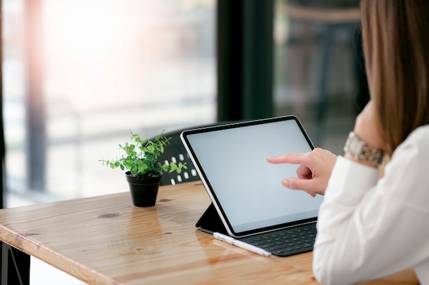 Cropped strzał kobieta używa pastylkę podczas gdy siedzący w co-workspace.