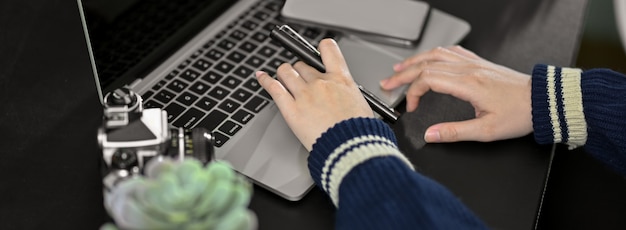 Cropped strzał pracuje na laptopie na czerń stole bizneswoman