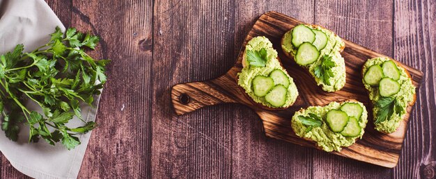 Crostini z marchewką awokado, ogórkami i ziołami na drewnianej tablicy