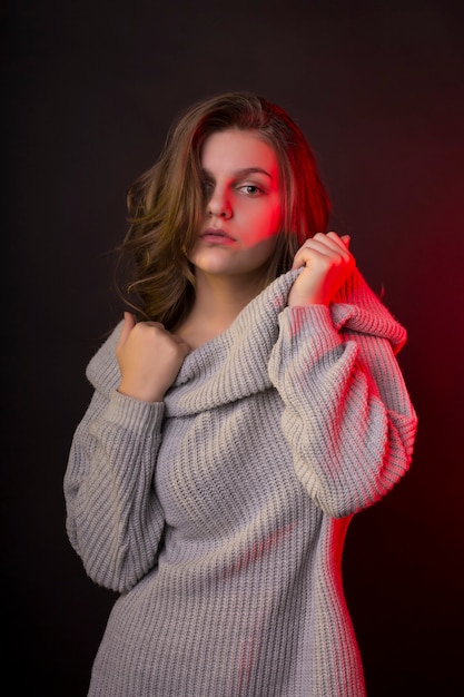 Cudowna młoda kobieta pozuje w swetrze z czerwonym światłem